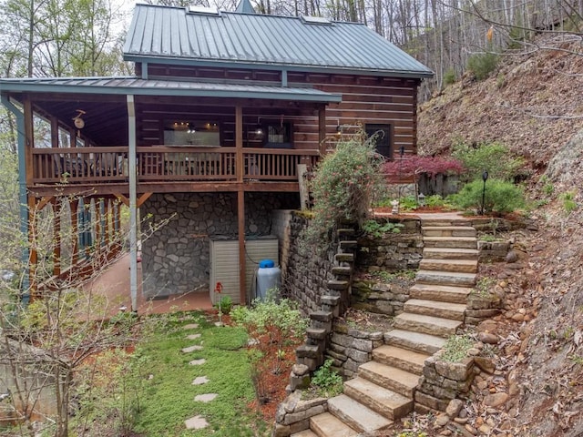 exterior space featuring a deck, metal roof, stone siding, and stairs