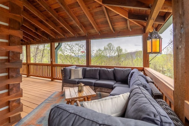 sunroom / solarium featuring a wealth of natural light, beam ceiling, and an outdoor hangout area