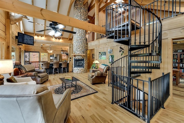 living area with wood walls, ceiling fan, a high ceiling, and wood finished floors