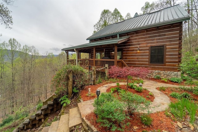 rear view of house featuring log exterior, metal roof, and a standing seam roof