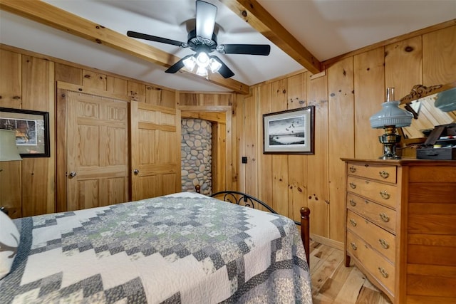 bedroom with light wood-style flooring, wood walls, and beamed ceiling