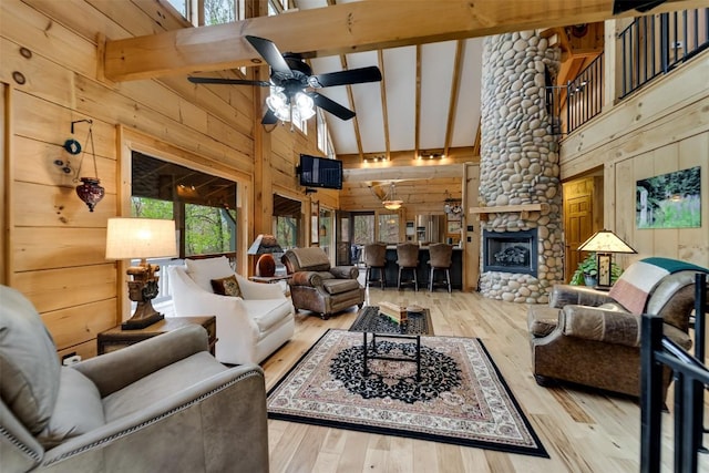 living area featuring high vaulted ceiling, wooden walls, wood finished floors, and ceiling fan