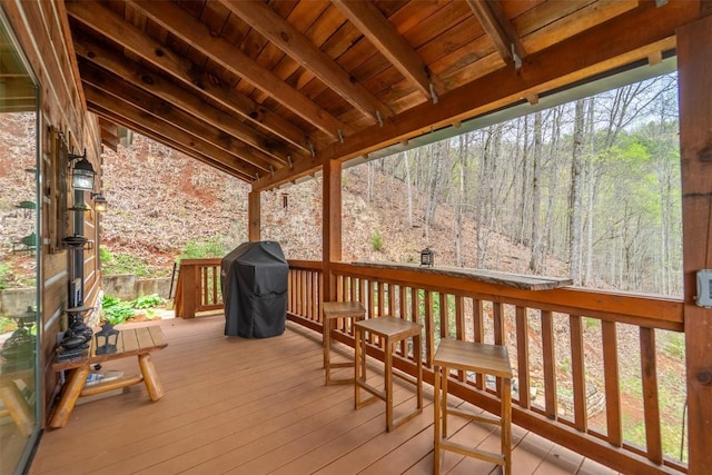 wooden terrace featuring a forest view and area for grilling