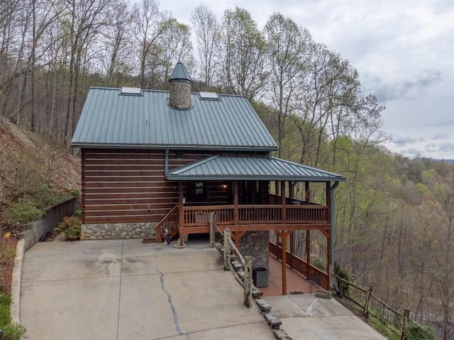 view of outbuilding featuring a view of trees, cooling unit, and a porch