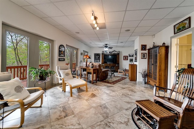 living room featuring a ceiling fan and a drop ceiling