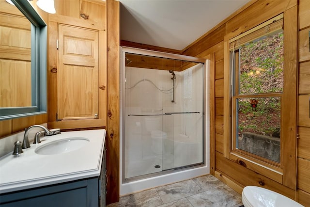bathroom featuring wooden walls, toilet, a stall shower, and vanity