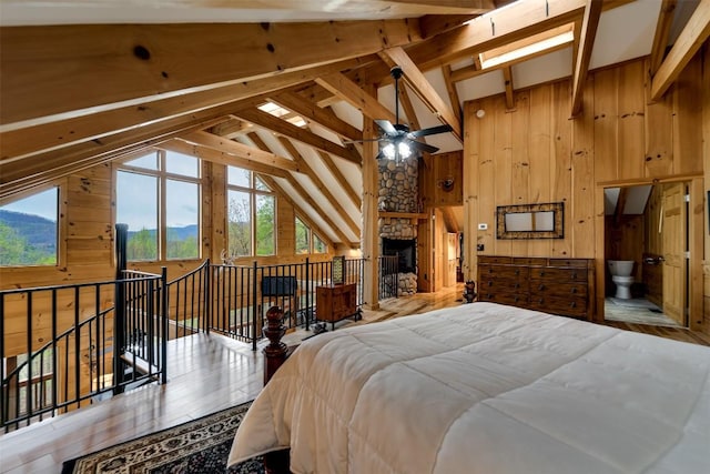 bedroom with wood finished floors, wood walls, and vaulted ceiling with beams