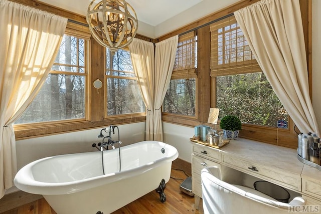 bathroom featuring an inviting chandelier, a freestanding bath, and wood finished floors