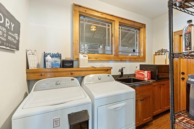 clothes washing area featuring dark wood-style flooring, cabinet space, a sink, and washer and clothes dryer