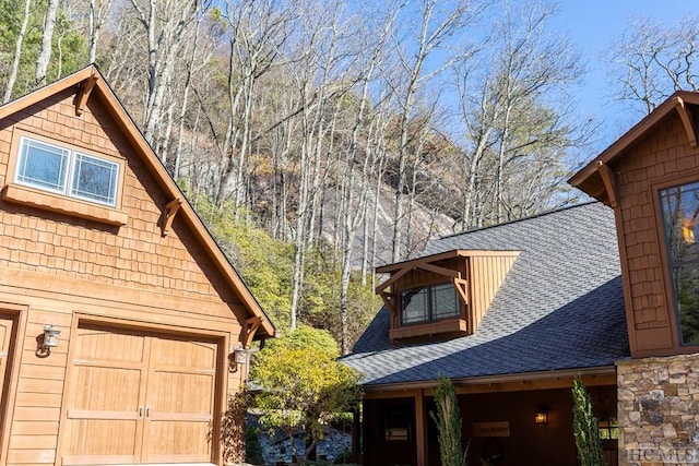 view of property exterior featuring a garage and a shingled roof