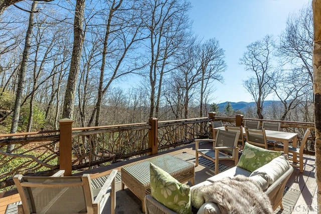 wooden deck featuring outdoor dining area, a mountain view, and an outdoor hangout area