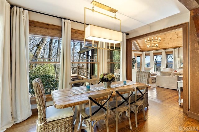 dining space featuring vaulted ceiling, a notable chandelier, and wood finished floors