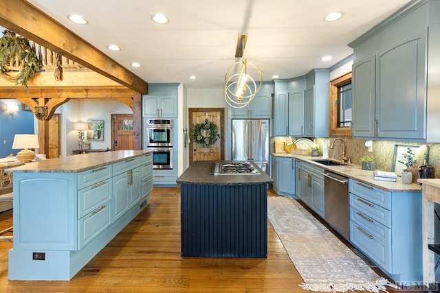 kitchen with hardwood / wood-style flooring, a sink, a kitchen island, appliances with stainless steel finishes, and backsplash