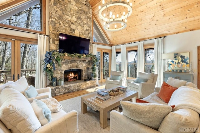 living room with a chandelier, wood finished floors, a wealth of natural light, and a stone fireplace