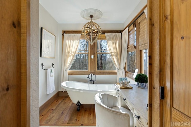 full bathroom featuring a freestanding tub, an inviting chandelier, and wood finished floors