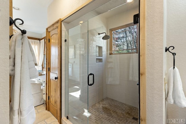 bathroom featuring a textured wall and a stall shower