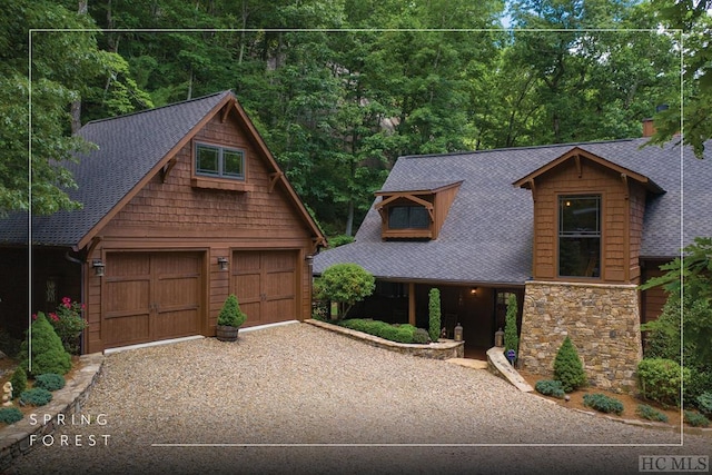 chalet / cabin featuring an outbuilding, stone siding, roof with shingles, and a detached garage