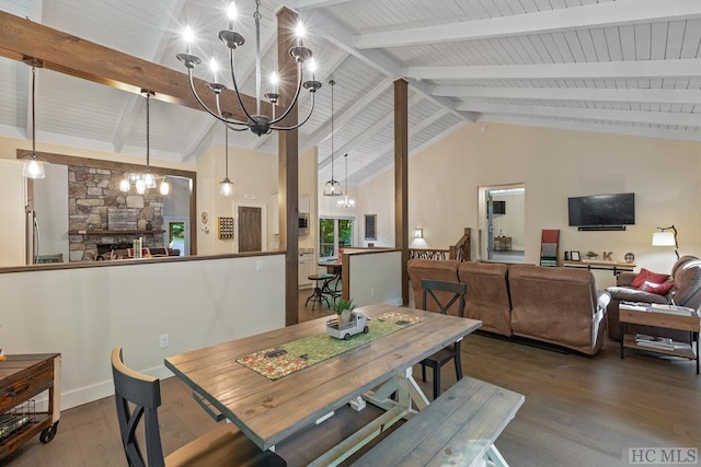 dining space featuring hardwood / wood-style flooring, an inviting chandelier, high vaulted ceiling, a fireplace, and beamed ceiling