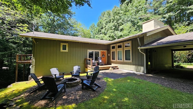 back of property with a yard and a fire pit