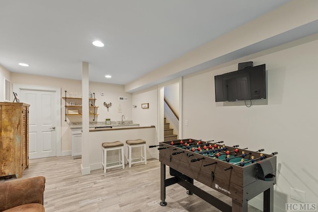 recreation room with sink and light wood-type flooring