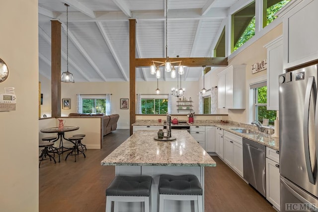 kitchen with white cabinetry, a kitchen breakfast bar, a center island, stainless steel appliances, and an inviting chandelier