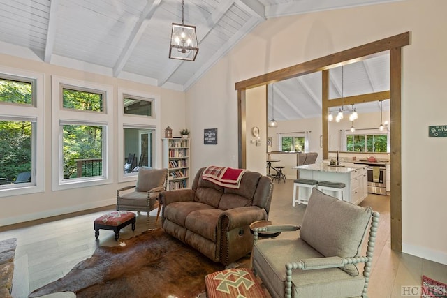 living room featuring an inviting chandelier, a healthy amount of sunlight, and beamed ceiling