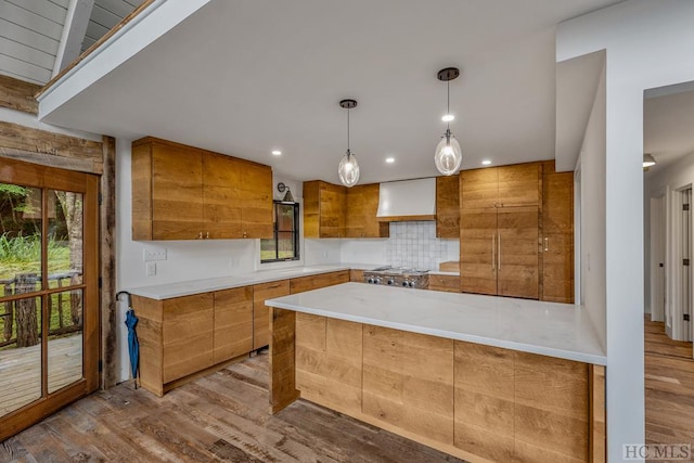 kitchen with tasteful backsplash, hanging light fixtures, stove, light wood-type flooring, and wall chimney exhaust hood