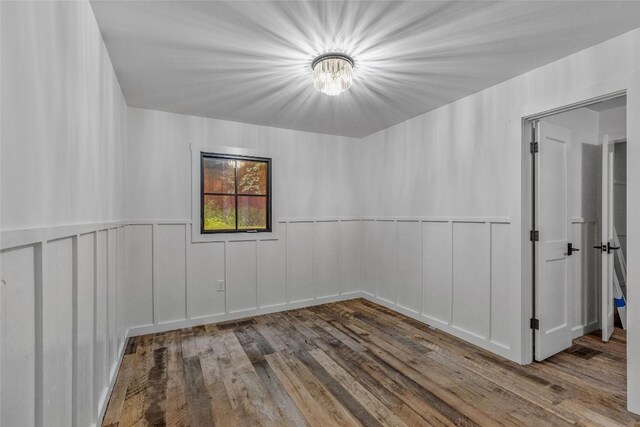 453 Bright Mountain Rd, Cullowhee, NC 28723 - unfurnished room featuring wood finished floors, a chandelier, a decorative wall, and wainscoting