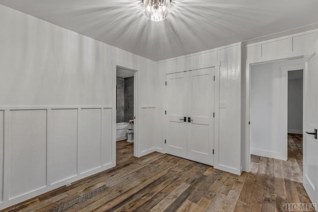 unfurnished bedroom featuring hardwood / wood-style floors, ensuite bath, and a closet