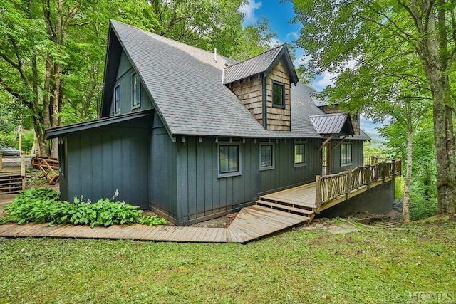 rear view of property featuring a wooden deck and a lawn