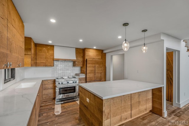 kitchen with a kitchen island, stainless steel stove, decorative light fixtures, dark hardwood / wood-style flooring, and light stone counters