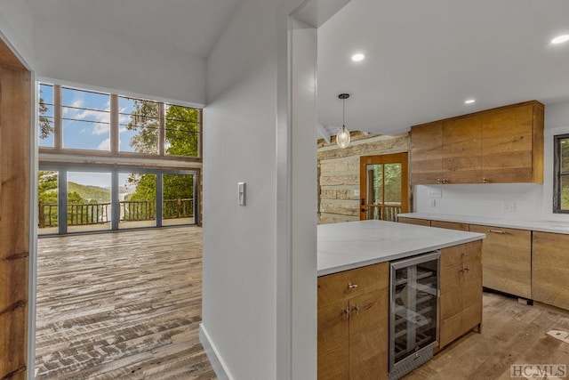 kitchen featuring wine cooler, a towering ceiling, light hardwood / wood-style flooring, and pendant lighting