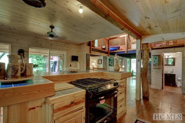 kitchen with light brown cabinetry, ceiling fan, black gas range, wooden ceiling, and light wood-type flooring