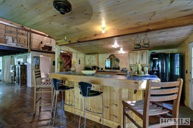 kitchen featuring black fridge, wooden ceiling, and light brown cabinetry