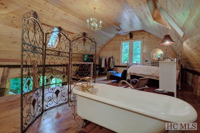 bedroom featuring wooden walls, a chandelier, lofted ceiling with skylight, and hardwood / wood-style floors