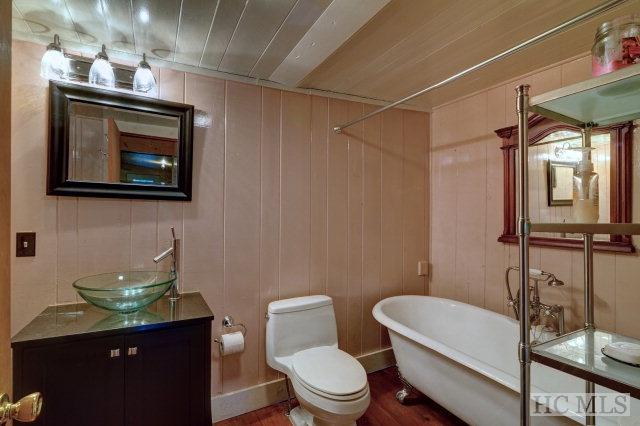 bathroom featuring toilet, vanity, a washtub, and wood walls