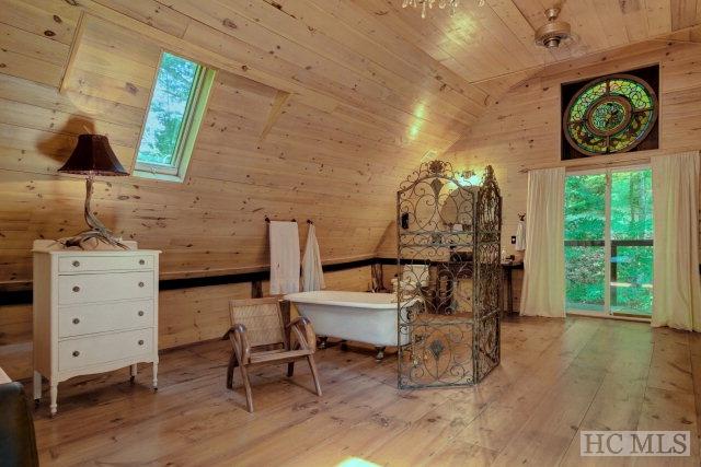 interior space with wood-type flooring, lofted ceiling with skylight, wood walls, and wooden ceiling