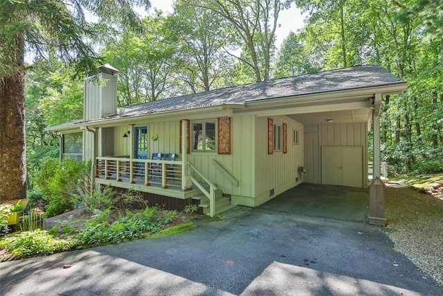 ranch-style house featuring a chimney, a carport, crawl space, aphalt driveway, and board and batten siding