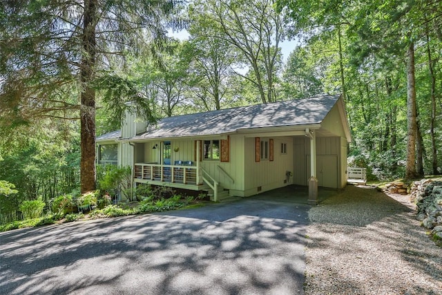 single story home featuring driveway, covered porch, a carport, crawl space, and board and batten siding