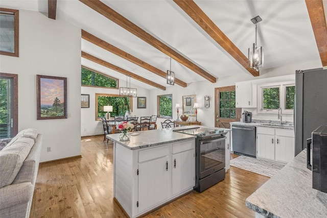 kitchen with a kitchen island, a sink, appliances with stainless steel finishes, white cabinetry, and a chandelier