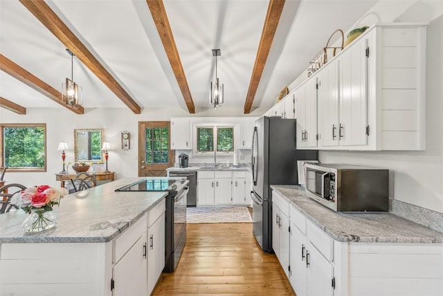 kitchen featuring electric range, light wood-style flooring, a sink, stainless steel microwave, and a center island