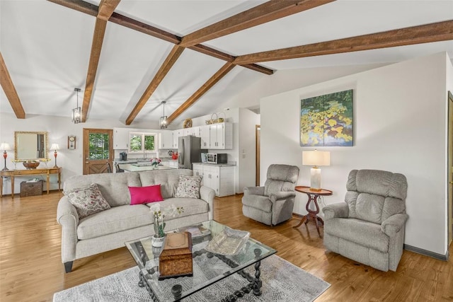 living area featuring lofted ceiling with beams and light wood-style flooring