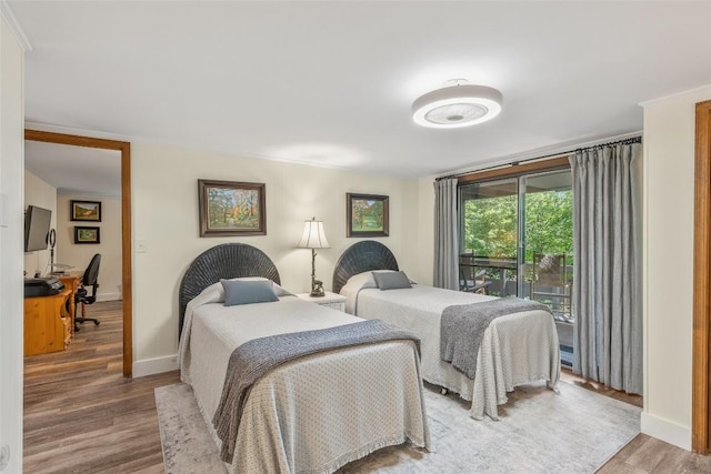 bedroom featuring access to exterior, baseboards, and wood finished floors