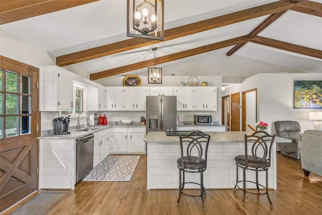 kitchen featuring a sink, lofted ceiling with beams, white cabinetry, stainless steel appliances, and light wood finished floors