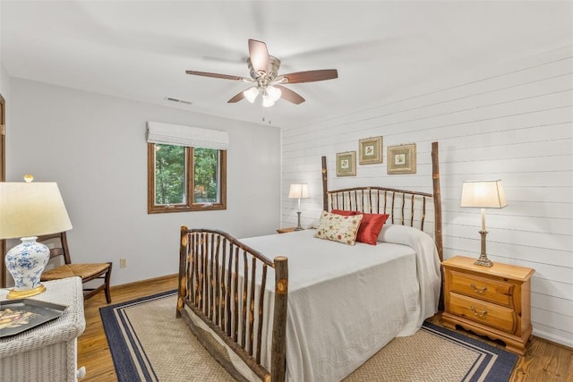 bedroom featuring a ceiling fan, wood finished floors, visible vents, and baseboards