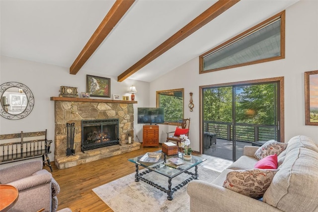 living room with a stone fireplace, vaulted ceiling with beams, and wood finished floors