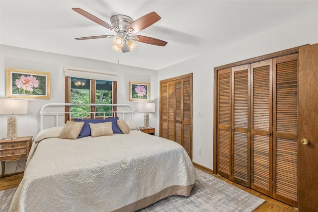 bedroom with light wood finished floors, two closets, baseboards, and a ceiling fan