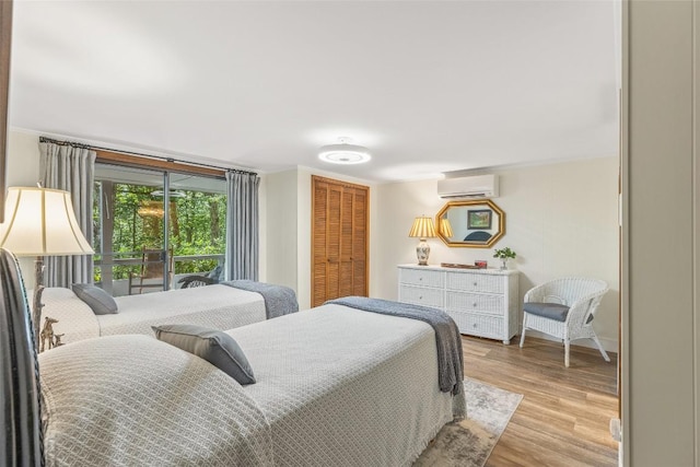 bedroom featuring light wood-type flooring, a closet, and a wall mounted AC