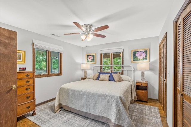 bedroom featuring visible vents, multiple windows, baseboards, and wood finished floors