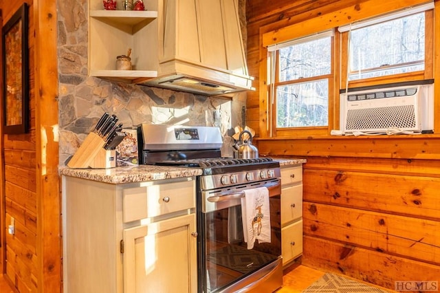 kitchen with gas stove, cooling unit, premium range hood, backsplash, and wooden walls